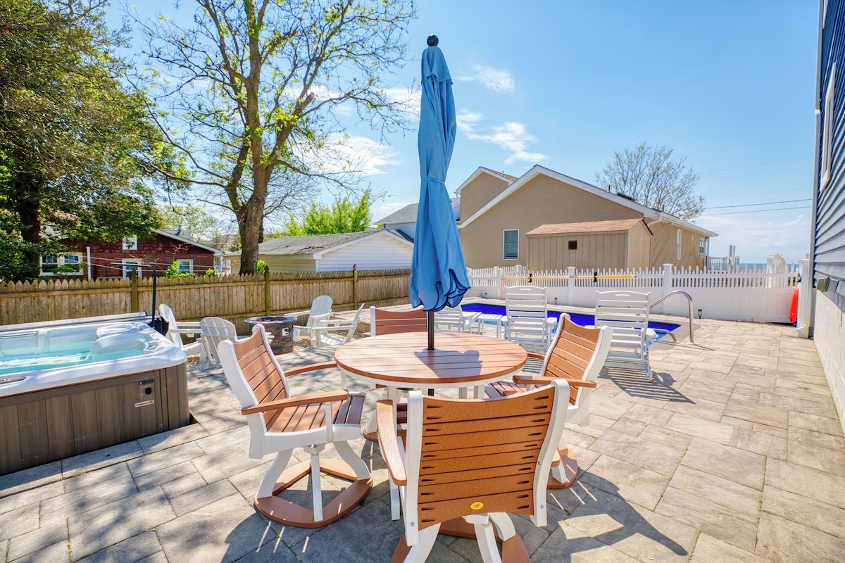 Backyard patio with hot tub, dining table, and fire pit