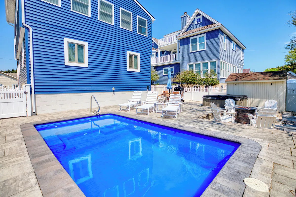 Heated in-ground pool and paver patio beside the blue beach house